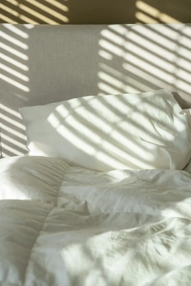 A bed made with white linen and pillows