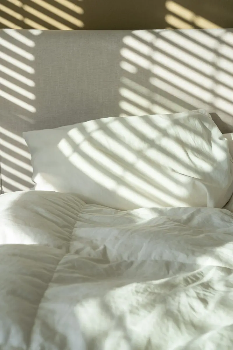 A bed made with white linen and pillows