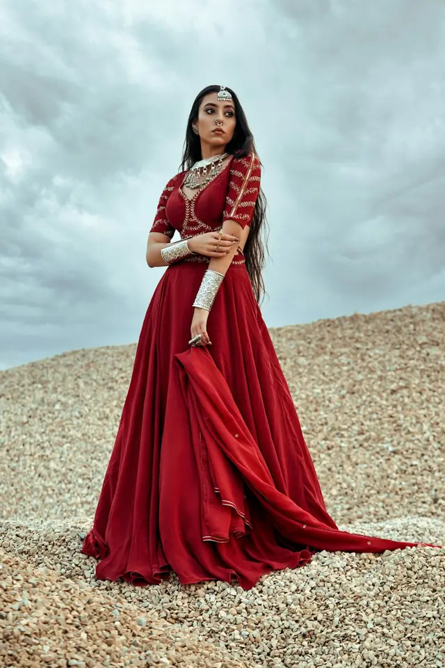Woman in a flowing red ethnic outfit on a hillside